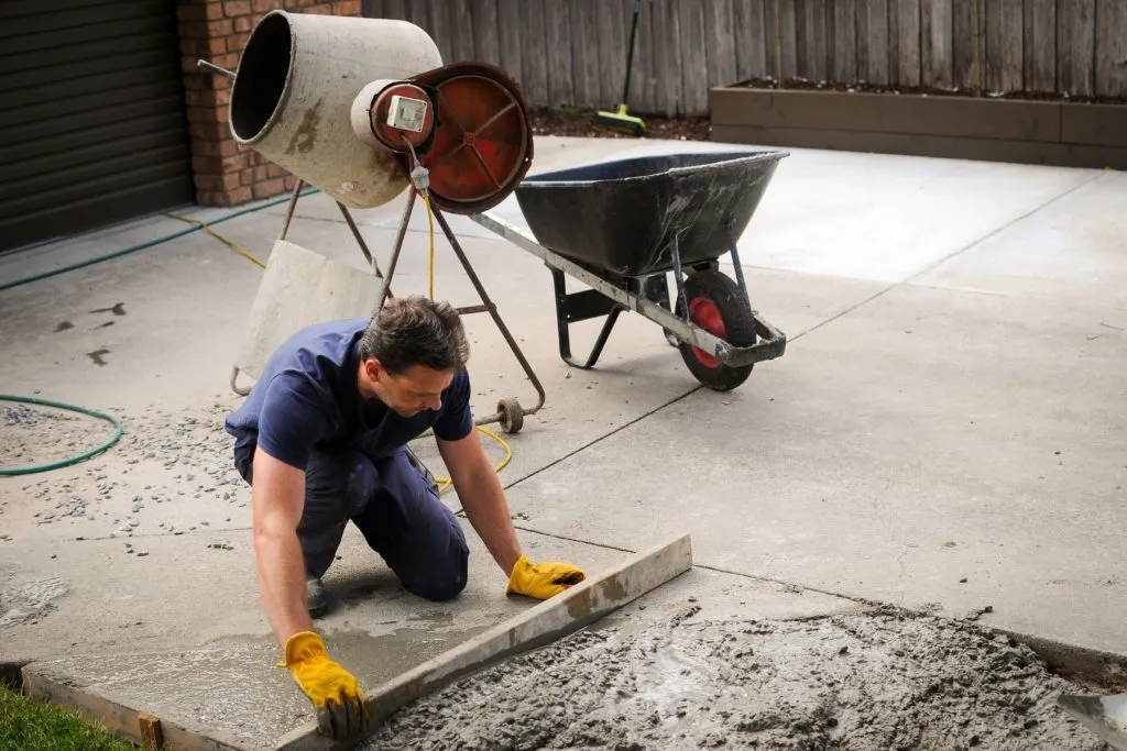 Concrete crew screeding a fresh driveway overlay during resurfacing in Austin