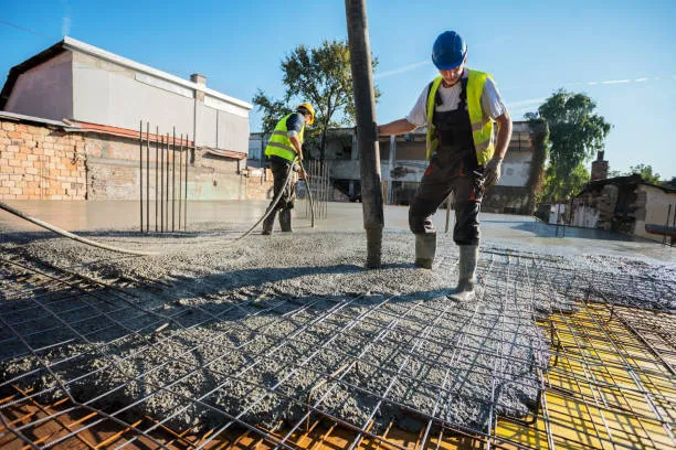 Crew pouring and spreading concrete over rebar for a slab in Austin