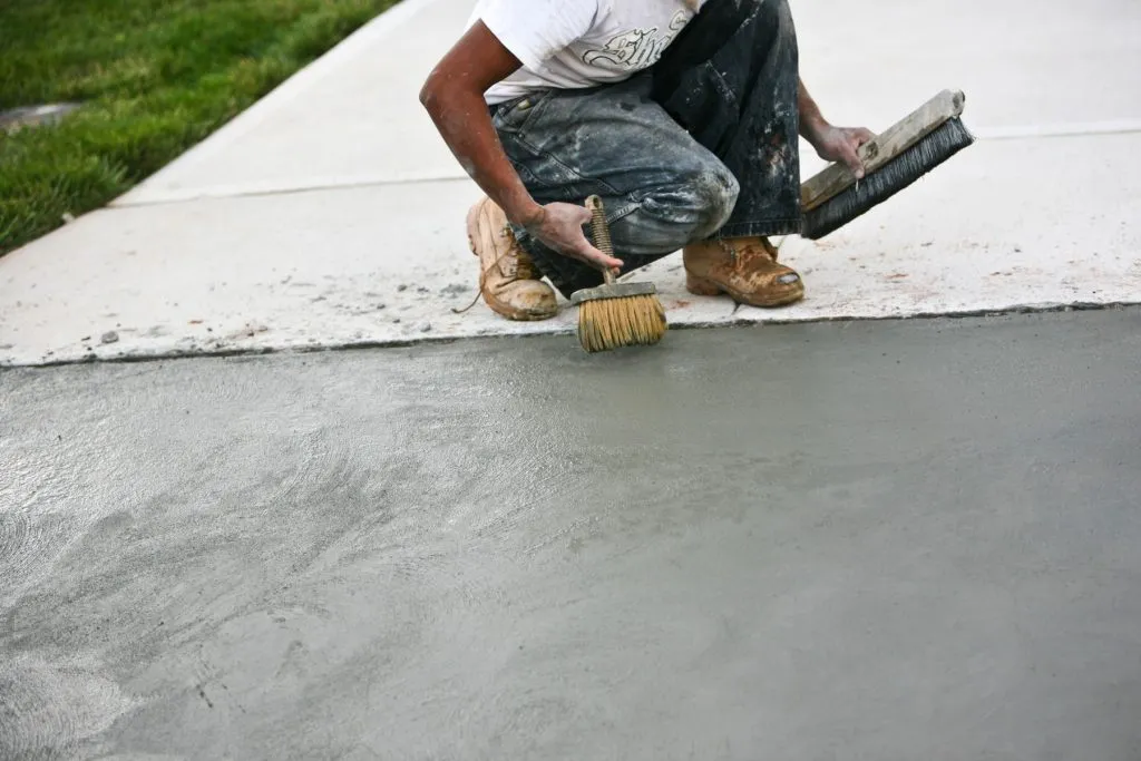 Concrete finisher smoothing a freshly poured Austin driveway with a float